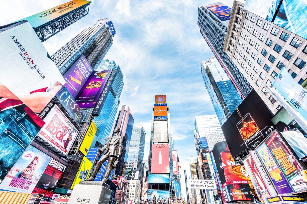 New York City, USA - October 28, 2017: Manhattan NYC buildings of midtown Times Square, Broadway avenue road, Duffy Square with many crowd people, skyscrapers looking up